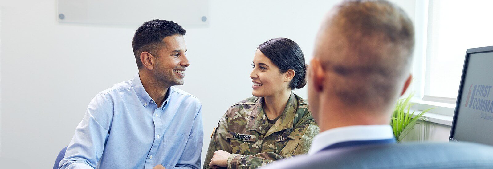 A smiling married couple chats with a loan advisor