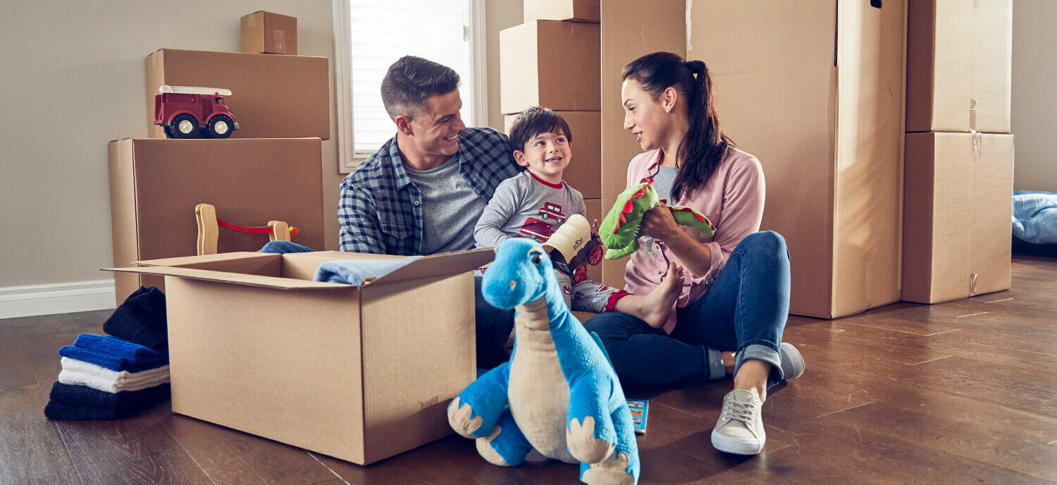 A smiling family playing with their young son on the floor with toys