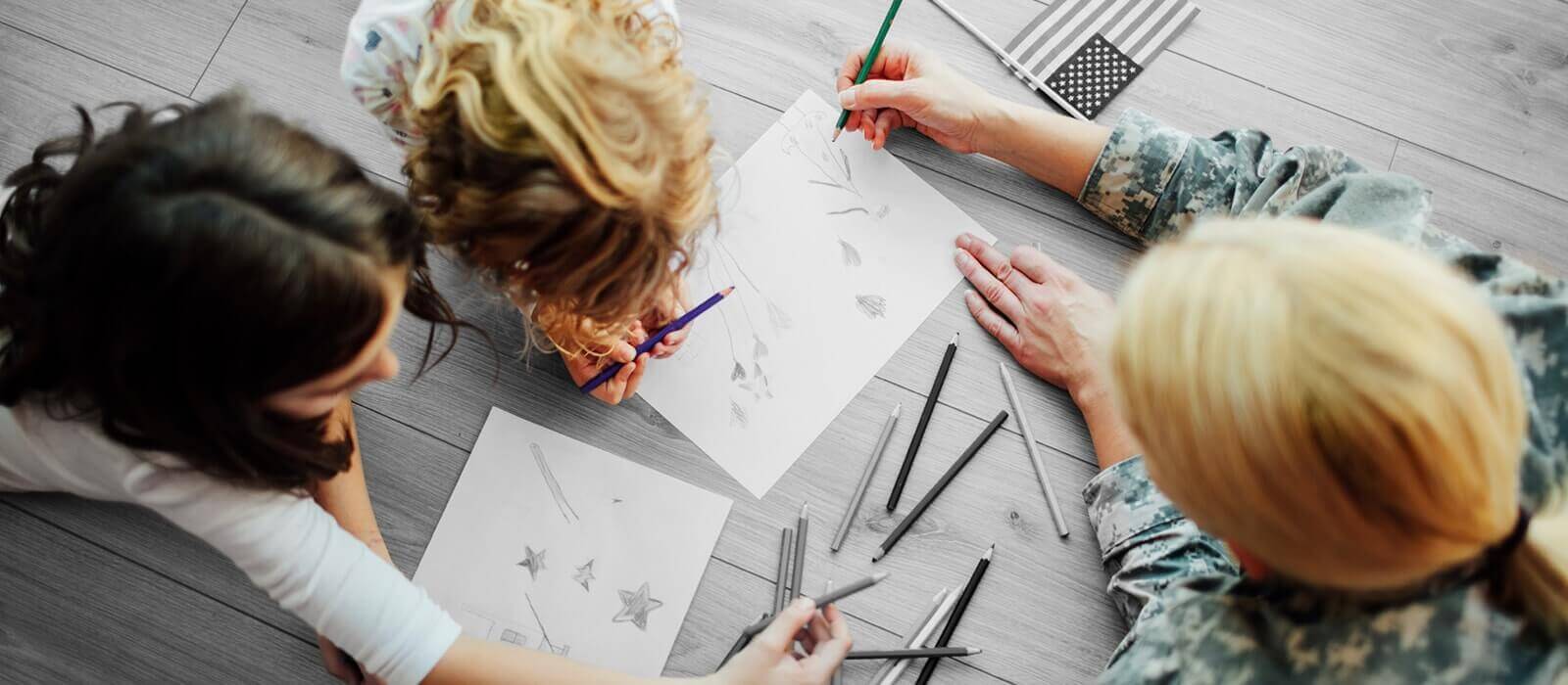 Picture of a mother and two girls drawing on the floor.